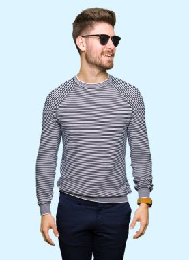 Genç yakışıklı uzak tarafına yüzünde, doğal ifade gülümseme ile seyir giyen güneş gözlüğü adam. Kendine güvenen gülüyor.