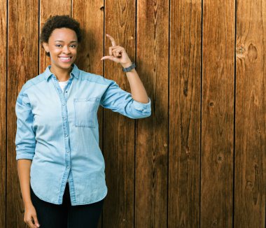 Genç güzel Afrikalı-Amerikalı kadın izole arka plan gülümseyen ve süre seyir ve kamera boyutu işaret parmaklarıyla yapıyor el ile kendine güvenen el hareketi yüzünden. Ölçü kavramı.