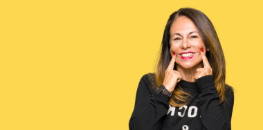 Kaya ve rulo kazak giyen güzel orta yaş kadın açık ağız ile gülümseyen, parmaklar işaret ve neşeli gülümseme zorlayarak