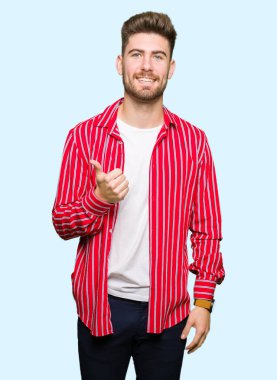 Kırmızı gömlek giyen genç yakışıklı adam el ile jest kadar mutlu thumbs yapıyor. Başarı gösteren kameraya bakarak ifadeyi onaylama.