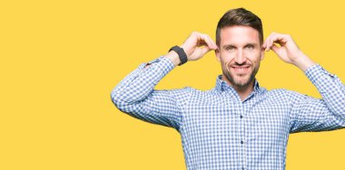 Yakışıklı iş adamı mavi parmak, komik jest gülen çekerek kulaklarıyla gözleri. Seçmelere sorun