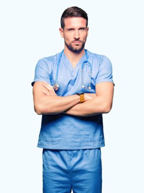 Yakışıklı Doktor izole arka plan şüpheci ve sinir, onaylamayan ifade yüz çapraz kolları üzerinde tıbbi üniforma giyen adam. Negatif kişi.
