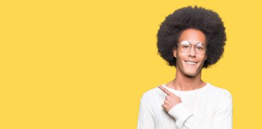 Neşeli bir gülümseme ile el ve parmak kadar yan yüzünde mutlu ve doğal ifade ile işaret yüz ile gözlüklü afro saçlı genç Afro-Amerikan adam
