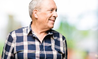 Yakışıklı yaşlı adam rahat gömlek giyen yüzünde gülümseme, doğal ifade ile yan bakıyor. Gülmekten emin.