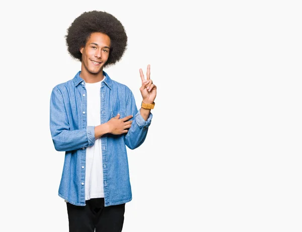 年轻的非洲裔美国男子与非洲头发微笑与快乐的脸眨眼在相机做胜利标志 — 图库照片