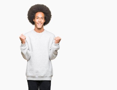 Afro saçlı genç afro-amerikan adam spor sweatshirt giyen kutlayan şaşırmış ve kollarını kaldırdı ve gözleri açık başarı için şaşırttı. Kazanan kavramı.
