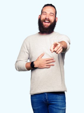 Rahat kazak giyen genç sarışın adam Gülüyor, parmağını göğsüne dayadan kameraya işaret ederek, utanç ifadesi