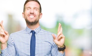 Yakışıklı iş adamı geçiş parmakları umut ve gözleri kapalı ile gülümseyen kravat takıyor. Şans ve batıl kavramı.