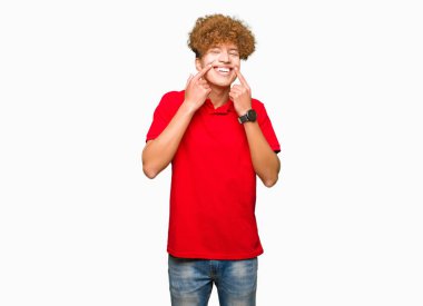 Afro saçlı Genç yakışıklı adam kırmızı t-shirt giyen açık ağız ile gülümseyen, parmaklar işaret ve neşeli gülümseme zorlamak