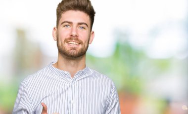 Hareketi el ile mutlu Yaşasın yapan genç yakışıklı erkek. Başarı gösteren kameraya bakarak ifade onaylama.