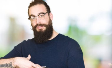 Uzun saç ve sakal acele işaretleme izlemek için zaman, sabırsızlık, üzgün ve kızgın son tarih gecikme için gözlük takan genç hipster adamla