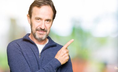 Bir kazak giyen orta yaş yakışıklı adam reklam, ciddi ve sakin yüz gösteren yan el parmağı ile Işaret