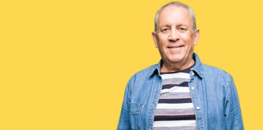 Yakışıklı yaşlı adam yüzünde mutlu ve serin bir gülümseme ile kot ceket giyiyor. Şanslı kişi.