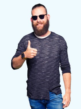 Genç hippi erkek hareketi el ile mutlu yaşasın yaparken güneş gözlüğü takıyor. Kameraya bakarak başarı gösteren ile ifade onaylama.