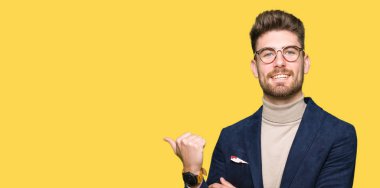 Seyir ve başparmak yanında yukarıyı mutlu yüz ile gülümseyen gözlüklü genç yakışıklı iş adamı.