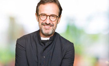 Katolik giyen orta yaş rahip adam alma veya jest vererek birlikte el avuç içi ile gülen robe. Ayrı tutma ve koruma