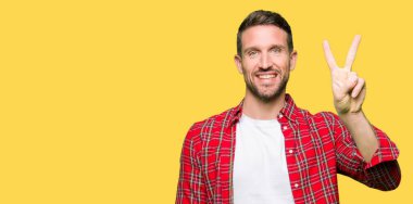Yakışıklı adam rahat gömlek gösteren giyen ve emin ve mutlu gülümserken parmakları ile iki numara işaret.