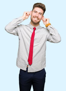 Genç yakışıklı iş adamı gülen çekerek kulaklarıyla parmaklar, komik jest. Seçmelere sorun