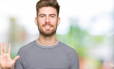 Çizgili süveter gösterme ve parmakları ile işaret giyen genç yakışıklı adam kendinden emin ve mutlu gülümseyerek süre beş numara.