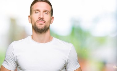 Yakışıklı adamın Casual beyaz t-shirt eller birlikte giydiğini ve parmakları rahat ve neşeli gülümseyen geçti. Başarı ve iyimser