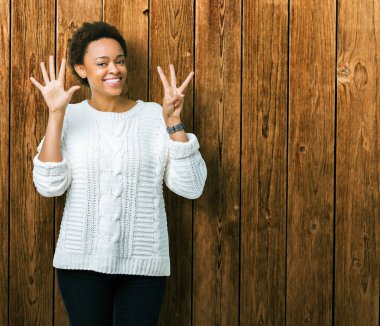 Güzel genç Afro-Amerikan kadın giyiyor kazak gösterilen ve parmakları ile işaret izole arka plan üzerinde kendinden emin ve mutlu gülümseyerek süre sekiz numara.