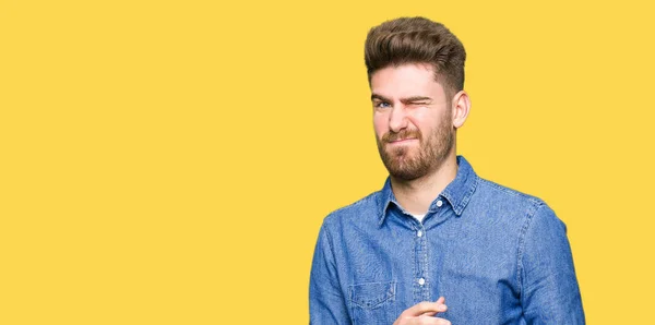 Young handsome blond man wearing casual denim shirt disgusted expression, displeased and fearful doing disgust face because aversion reaction. With hands raised. Annoying concept.