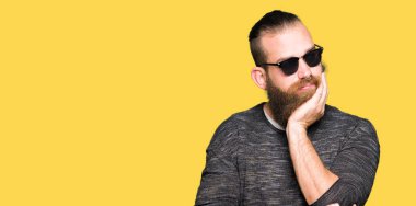 Düşünme seyir yorgun ve sıkılmış depresyon sorunları ile güneş gözlüğü takmış genç hipster adam silah geçti.