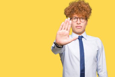 Afro giyen gözlük ile genç yakışıklı iş adamı el avuç ile şarkı durdurmak yapıyor. Yüz üzerinde negatif ve ciddi jest ile uyarı ifadesi.