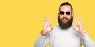 Genç hipster adam giyen güneş gözlüğü rahatla ve gülümseyen gözlerle kapalı parmak jestle meditasyon yapıyor. Yoga kavramı.