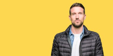 Yakışıklı adam yüzünde ciddi bir ifade ile bir gevşek kış palto giyiyor. Basit ve doğal kameraya bakıyor.