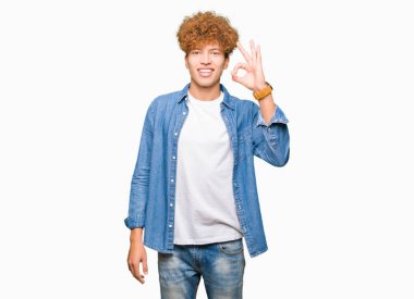 Genç yakışıklı adam ile afro saç giyen denim ceket gülümseyen pozitif yapıyor ok işareti ile el ve parmaklar. Başarılı ifade.