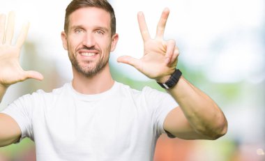 Casual beyaz t-shirt gösterme ve parmakları ile işaret giyen yakışıklı adam kendinden emin ve mutlu gülümseyerek süre sekiz numara.