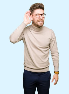 Gözlüklü bir işitme söylenti ya da dedikodu için dinleme kulak üzerinde el ile gülümseyen genç yakışıklı iş adamı. Sağırlık kavramı.