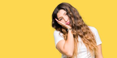 Casual beyaz t-shirt düşünme seyir giyen genç güzel kadın yorgun ve sıkılmış çapraz silah depresyon sorunları ile.