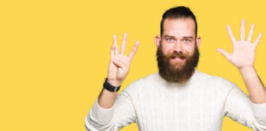 Kış kazak gösterme ve parmakları ile işaret giyen genç hipster adam numara 9 kendinden emin ve mutlu gülümseyerek süre.