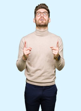 Gözlüklü genç yakışıklı iş adamı şaşırtmak ve yukarıya bakıp parmakları ile işaret şaşırttı ve silah kaldırdı.