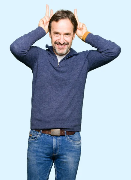 バニー耳として頭の上に指で面白いとクレイジーポーズセーターを着て中年のハンサムな男は 陽気な笑顔 — ストック写真