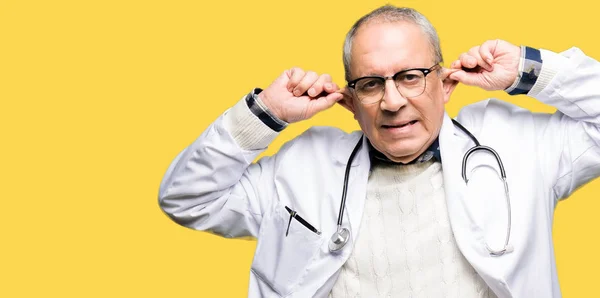 Przystojny Starszy Lekarz Człowiek Ubrany Medyczny Płaszcz Uśmiechnięty Ciągnięcie Uszy — Zdjęcie stockowe