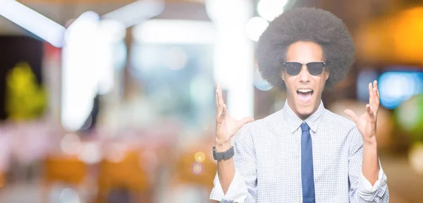 腕を上げて目を閉じて興奮して成功を祝うサングラスをかけたアフロヘアの若いアフリカ系アメリカ人ビジネスマン 勝者のコンセプト — ストック写真