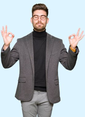 Genç yakışıklı iş adam gözlük rahatla ve gülümseyen gözlerle kapalı parmak jestle meditasyon yapıyor. Yoga kavramı.