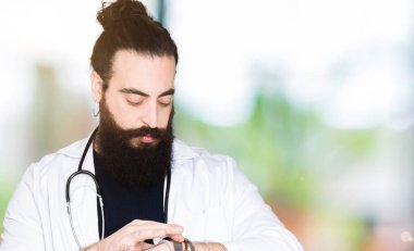 Doktor uzun saçlı tıbbi ceket ve kol saati, rahat ve kendinden emin zamanında kontrol stetoskop