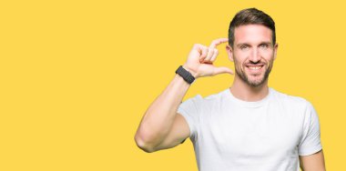 Casual beyaz gömlek gülümseyen ve süre seyir ve kamera boyutu işaret parmaklarıyla yapıyor el ile kendine güvenen el hareketi giyen yakışıklı adam. Ölçü kavramı.