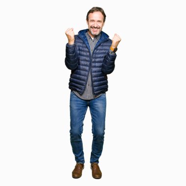 Kutlama kış ceket giyen orta yaş yakışıklı adam şaşırttı ve başarı için kaldırdı kollarını açarak hayret ve gözleri açık. Kazanan kavramı.