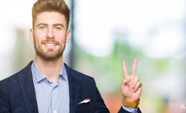 Mutlu yüz zafer işareti yaparken kameraya göz kırpıyor ile gülümseyen genç yakışıklı iş adam. İki numaralı.
