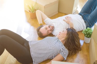 Orta yaş Senior romantik çift yerde yatıyor, yeni bir eve hareket için mutlu gülümseyen, rahatlatıcı ve ambalaj kutularının bir mola alarak