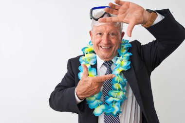 Kıdemli işadamı takım elbiseli, Hawaii Lei dalış gözlüğü takıyor izole edilmiş beyaz arka planda gülümsüyor ve elleri ve parmakları gülen yüzlü bir çerçeve yapıyor. Yaratıcılık ve fotoğrafçılık kavramı.