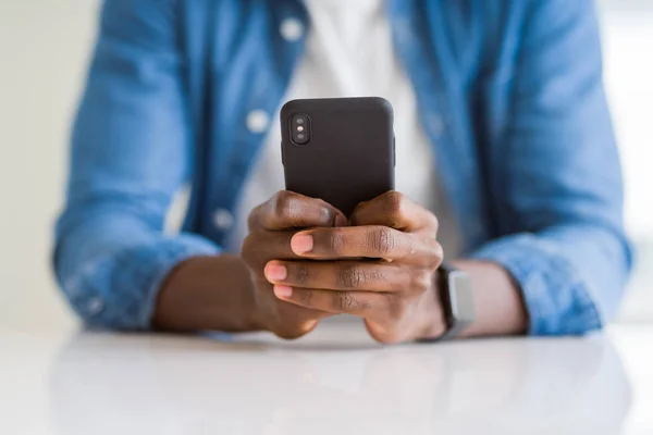 Fechar as mãos do homem africano usando smarpthone — Fotografia de Stock