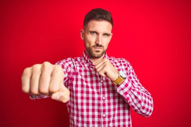 Genç ve yakışıklı bir adam kırmızı arka planda. Yumruk yumruğa dövüşme, agresif ve öfkeli saldırı, tehdit ve şiddet.