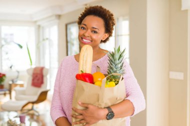 Kağıt torba dolu tutan genç güzel Afrikalı-Amerikalı kadın