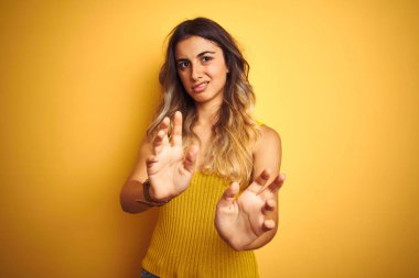 Sarı izole edilmiş arka plan yüz ifadesi üzerine tişört giyen genç ve güzel bir kadın tiksinti reaksiyonu yüzünden tiksinti ve korku dolu bir ifade takınıyor. Eller havada. Can sıkıcı bir kavram..